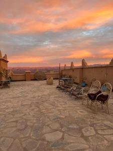 a group of chairs sitting on a patio with a sunset at Kasbah Ennakb in Nkob