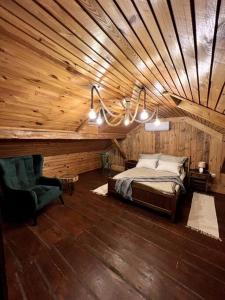 a bedroom with a wooden ceiling with a bed and a chair at Drewniana chata nad stawem in Krasiczyn