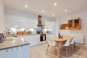a kitchen with a wooden table and white cabinets at Modern Spacious Bright 1-Bedroom Ground Floor Flat in Oxford