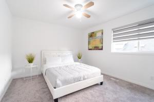 a white bedroom with a bed and a ceiling fan at Spacious & Modern by the Beach in White Rock