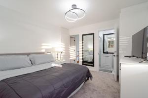 een witte slaapkamer met een bed en een televisie bij Spacious & Modern by the Beach in White Rock