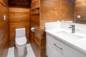 a bathroom with a toilet and a sink and wooden walls at Spacious & Modern by the Beach in White Rock