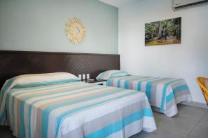 a bedroom with two beds with striped sheets at Hotel Camino Del Sol in Puerto Escondido