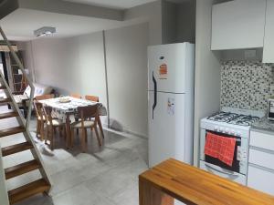 a kitchen with a white refrigerator and a table with chairs at VM 1254 - Departamento APART - con Cochera in Rosario