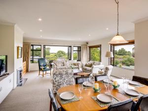 Busby Hill Villa - Havelock North Holiday Home في هافلوك الشمالية: غرفة معيشة مع طاولة طعام وغرفة معيشة