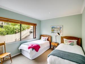 two beds in a room with a window at Busby Hill Villa - Havelock North Holiday Home in Havelock North