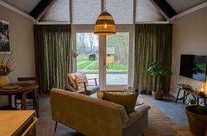 a living room with a couch and a large window at Gastenverblijf de Vense Weide in Venlo