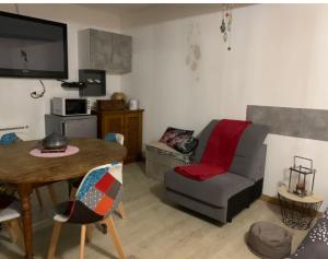 a living room with a table and a chair and a couch at Studio entier Tout confort in Le Gond-Pontouvre