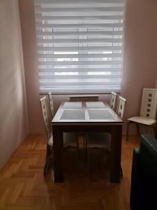 a dining room table and chairs in front of a window at Apartment Andjela in Belgrade