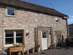 a stone cottage with a white door and windows at Brookside Barn in Bradwell