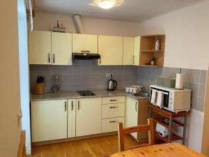 a kitchen with white cabinets and a microwave at TURISTIČNA KMETIJA STREVC in Solčava