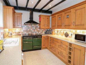 a kitchen with wooden cabinets and a green stove top oven at Arwel in Capel Garmon