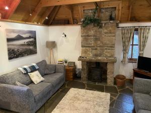 a living room with a couch and a stone fireplace at Tigh Phadraig at Marys Thatched Cottages in Elgol