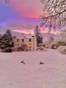 two birds flying in the snow in front of a house at Corrie Apartment in Appin