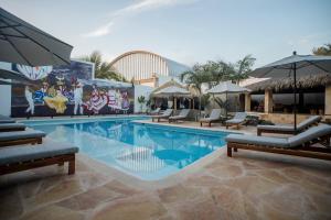 a swimming pool with chairs and umbrellas in a resort at Hotel Camino Del Sol in Puerto Escondido