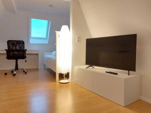 uma sala de estar com uma televisão de ecrã plano e uma cadeira em Rooftop Apartmens Ulm - komfortable neue Gemeinschaftsunterkunft im Herzen von Ulm - Raum 3 em Ulm