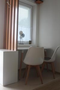 Una silla blanca y un escritorio en una habitación con ventana en Spa Apartmán Kováčová en Kováčová