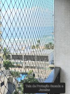 a chain link fence with a view of the ocean at Apartamento Praia de Pitangueiras Pé na Areia Vista para o Mar in Guarujá