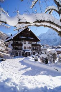 ein schneebedecktes Gebäude vor einem Berg in der Unterkunft Hotel Spielmann in Ehrwald