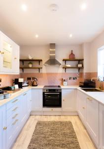 cocina con armarios blancos y fogones en Bright, immaculate, luxe Apartment minutes from Warwick - perfect for short & long breaks, en Warwick