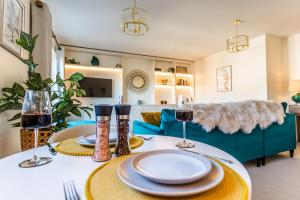 a dining table with two glasses of wine on it at Chic, immaculate, stylish Warwick apartment close to town & castle - perfect for short & long breaks in Warwick