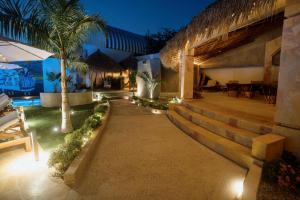 a house with a pathway leading to a patio with palm trees at Hotel Camino Del Sol in Puerto Escondido