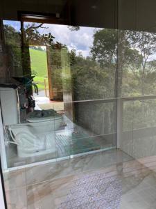 a bathroom with a glass window with a sink at Morada dos Colibris in Santo Antônio do Pinhal