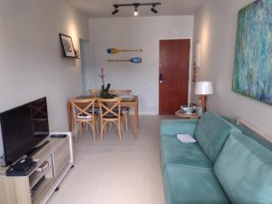 a living room with a green couch and a table at Edifício Monte Carmel in Guarujá
