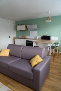un sofá púrpura en una sala de estar con cocina en Casa Ragazzi - Refait à neuf - Calme - Parking, en Lempdes