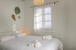 a white bedroom with two towels on a bed at Apopsis Tinos View in Triandáros