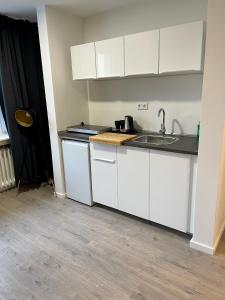 a kitchen with white cabinets and a sink at Aparthotel Neumünster City in Neumünster