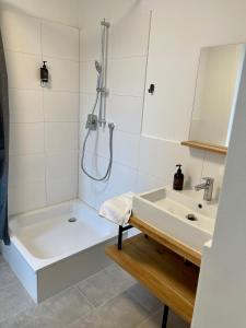 a white bathroom with a tub and a sink at Aparthotel Neumünster City in Neumünster