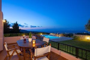 a patio with a table and chairs and a pool at AmElia Villa in Spanokhórion