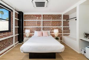 a bedroom with a brick wall and a bed with pink pillows at The Brick Boutique Hotel in Oceanside