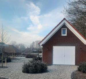 una casa de ladrillo rojo con garaje blanco en Gastenverblijf de Vense Weide en Venlo