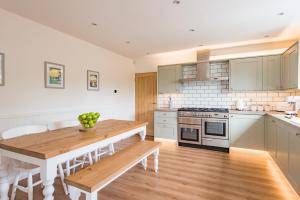 a kitchen with a wooden table and a stove top oven at Luxurious & Modern Large 5 Bed House, HotTub, Views! in Maidstone