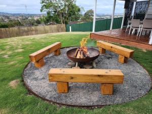 a fire pit with wooden benches and a fire pit at Waratah Holiday Home in Unanderra