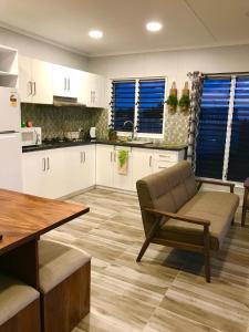 a kitchen with white cabinets and a table and a chair at Joe's Shack - A cosy oasis in Nadi close to the beach, supermarkets, restaurants, Denarau Island and the Marina. in Nadi