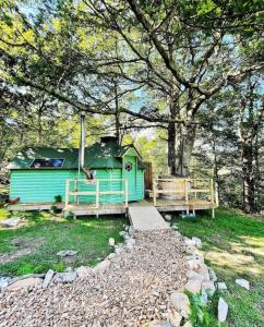 a green house with a bridge next to a tree at Woodland Cabin with Hot tub & log burner in Barmouth