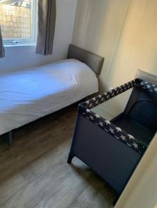een kleine slaapkamer met een bed en een stoel bij Chalet Toetje op de Veluwe in Hoenderloo