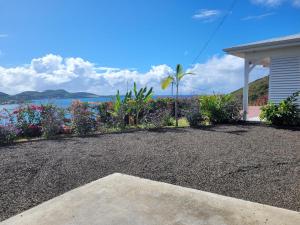 a house with a gravel driveway next to the water at VILLA INDEPENDANTE MAGNIFIQUE VUE MER DES CARAIBES in Le Marin