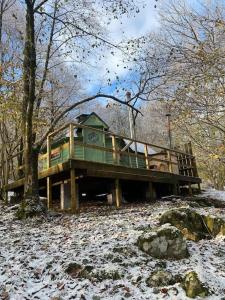 una casa sull'albero nel bosco con neve sul terreno di Tree Top Cabin with log burner & private hot tub a Barmouth