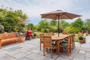 a patio with a wooden table and chairs and an umbrella at Luxurious & Modern Large 5 Bed House, HotTub, Views! in Maidstone