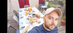 a man wearing a hat sitting at a table with food at Les Rêves D'Eglantine, maison d'hôtes in Saint-Cyr +16 photos