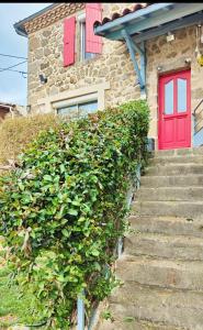 a red door on a house with a hedge at Les Rêves D'Eglantine, maison d'hôtes in Saint-Cyr