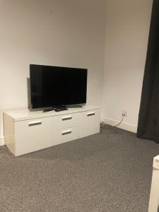 una TV a schermo piatto seduta sopra un centro di intrattenimento bianco di City Residencies - Thames View Greenwich a Londra