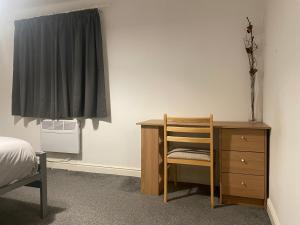 a bedroom with a desk and a chair next to a dresser at City Residencies - Thames View Greenwich in London