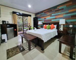 1 dormitorio con 1 cama y 2 bancos. en Calathea Lodge Monteverde en Monteverde Costa Rica