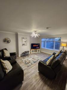 a living room with two couches and a tv at House on the Furrows in Luton