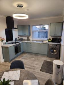 a kitchen with blue cabinets and a sink and a table at House on the Furrows in Luton